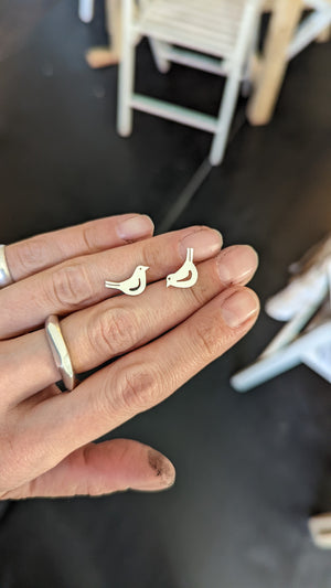 Student shows handmade silver bird stud earrings made in jewellery making workshop