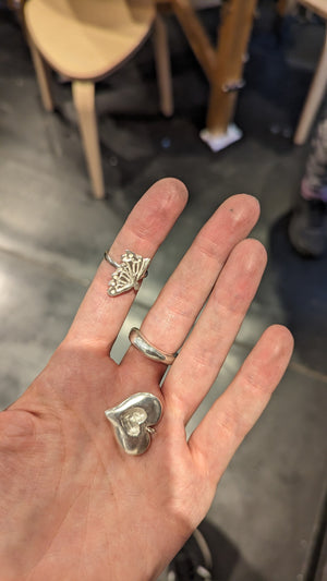 Student shows examples of handcrafted pendent and rings made in silver jewellery making workshop