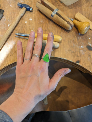 Student shows examples of silver and sea glass and stone rings made by students in silver making jewellery workshop