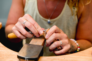 Student uses tools at workbench to finesse their handcrafted piece made in jewellery making workshop