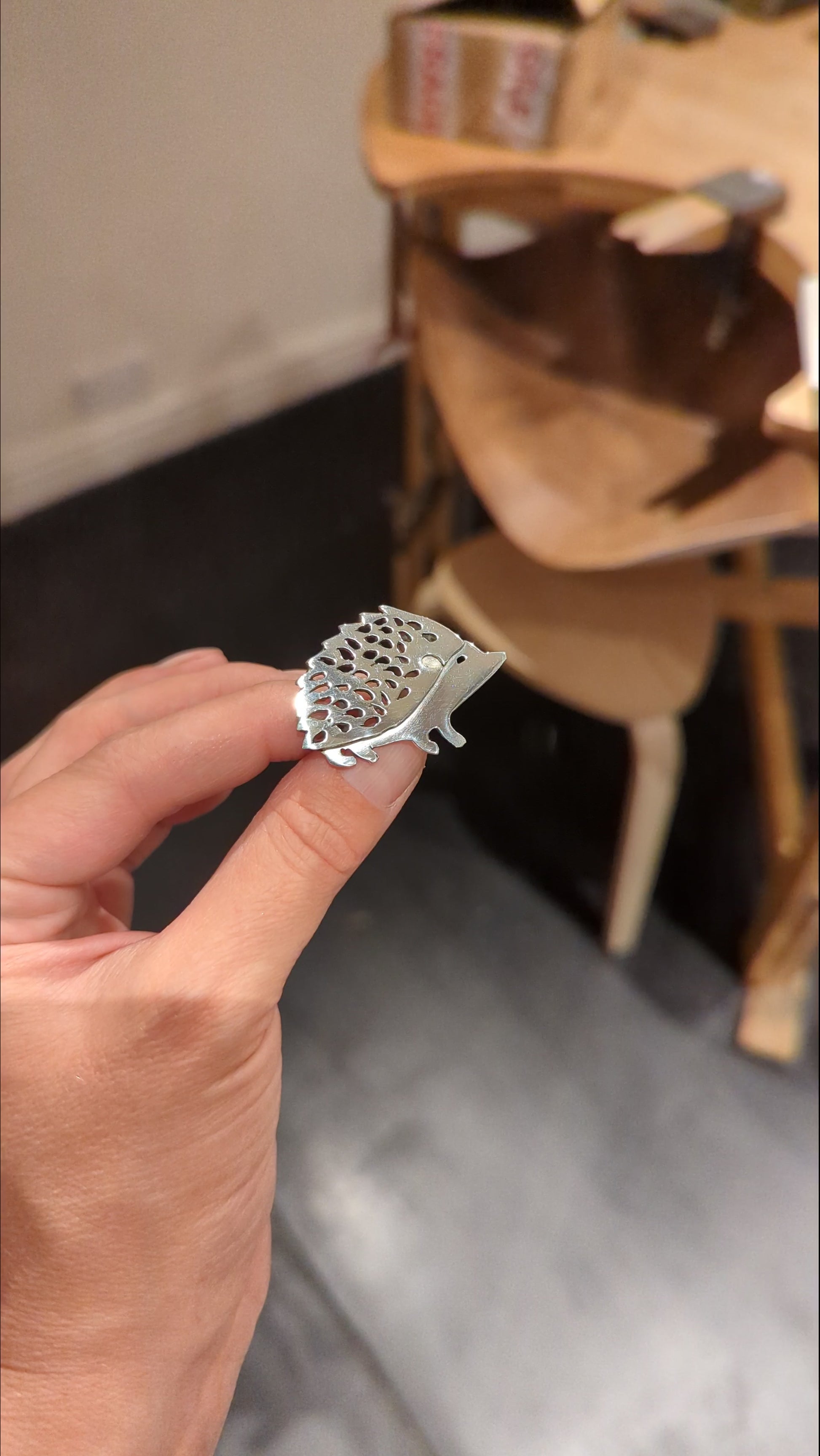 Student shows handcrafted silver hedgehog brooch made in jewellery making workshop