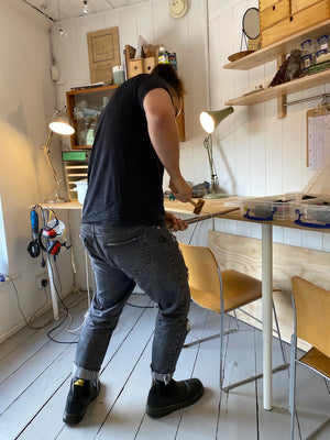 Student hammers handmade wedding band into shape in private jewellery making workshop Cardiff