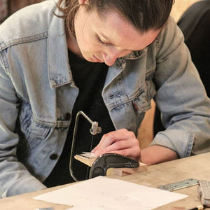 Student use saw to craft necklace in silver jewellery workshop