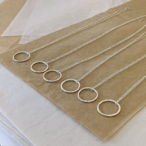 Showcase of handmade silver stacking rings as pendants on silver chain in jewellery making workshop
