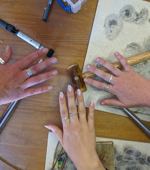 Students exhibit their handmade silver stacking rings on workshop bench made in jewellery making workshop