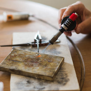 Student uses blow torch to shape and form handmade piece in silver jewellery making workshop